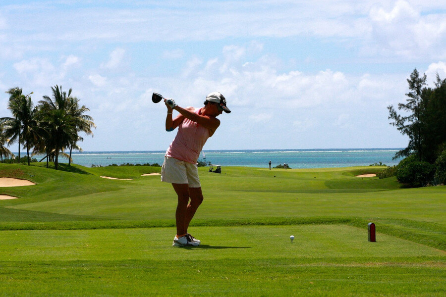 woman hitting golf ball with driver on golf course